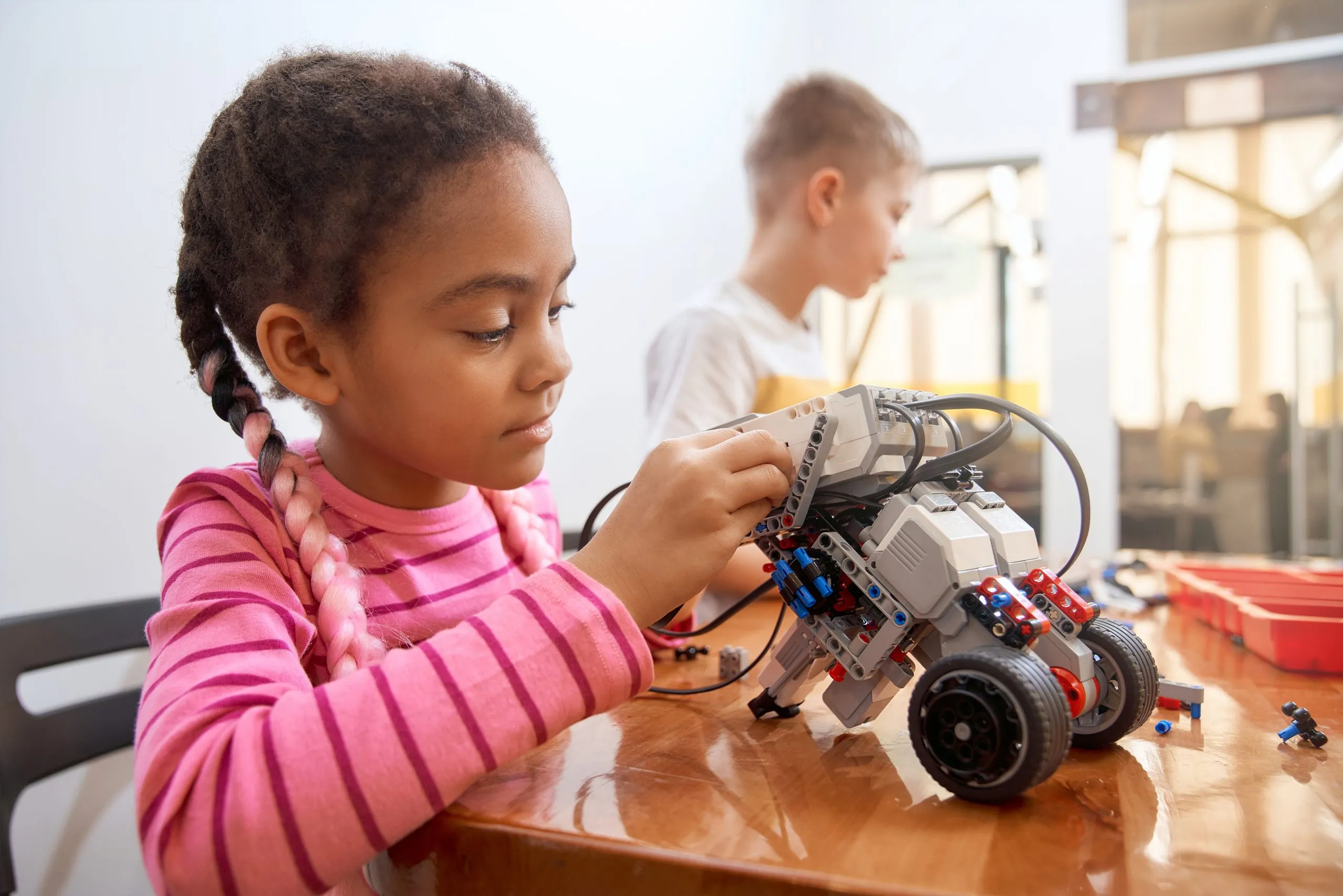 Niña construyendo un robot en un campamento tecnológico
