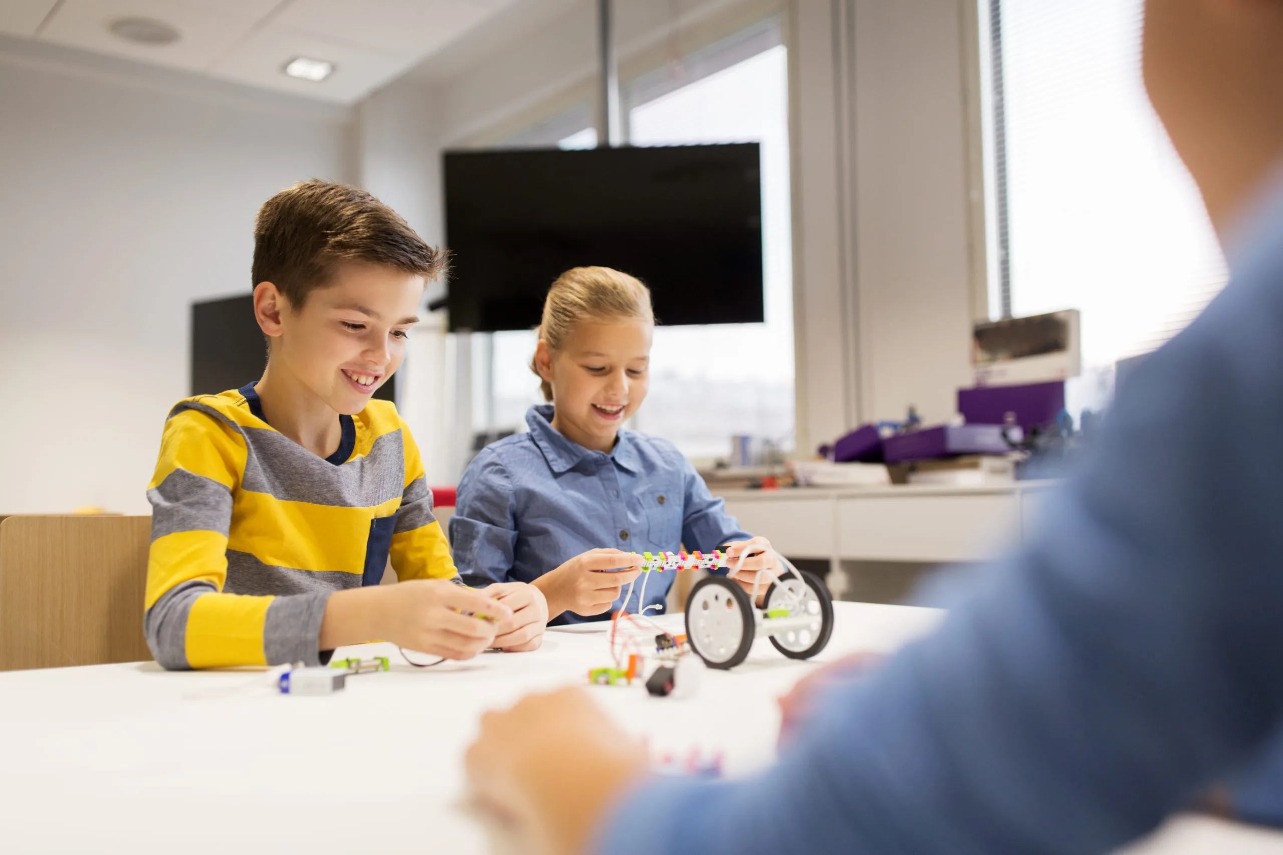Niños y niñas construyendo robots en clase de robótica educativa